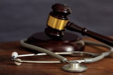 Law gavel and a stethoscope on a wooden desk, dark background